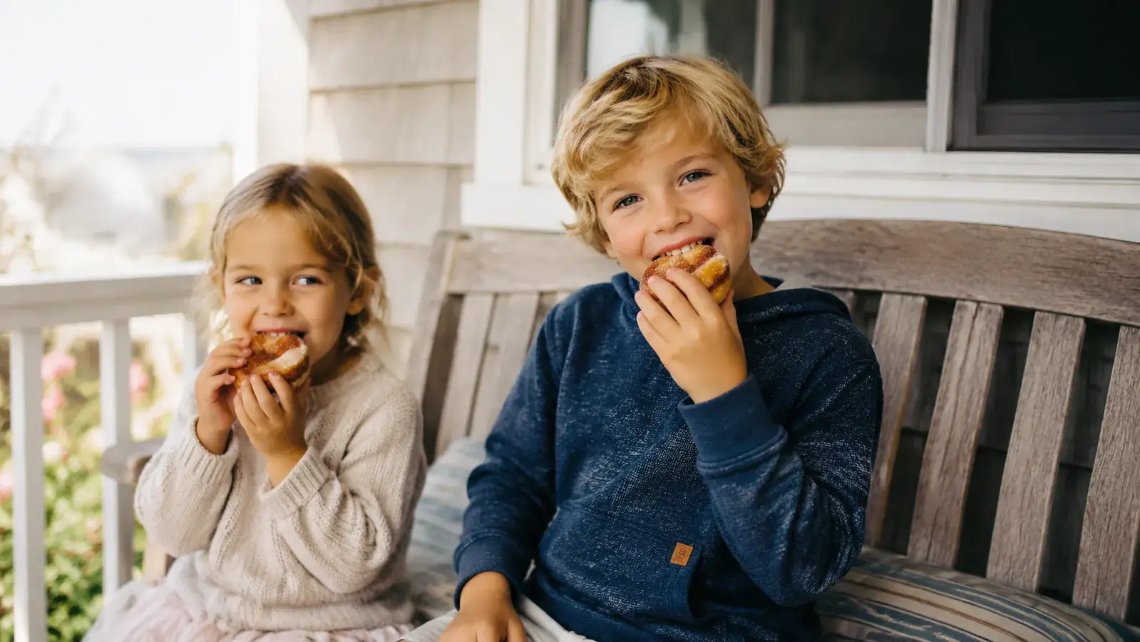 Grandkids eating mini donuts off a napkin on a porch table in a small Texas coastal town