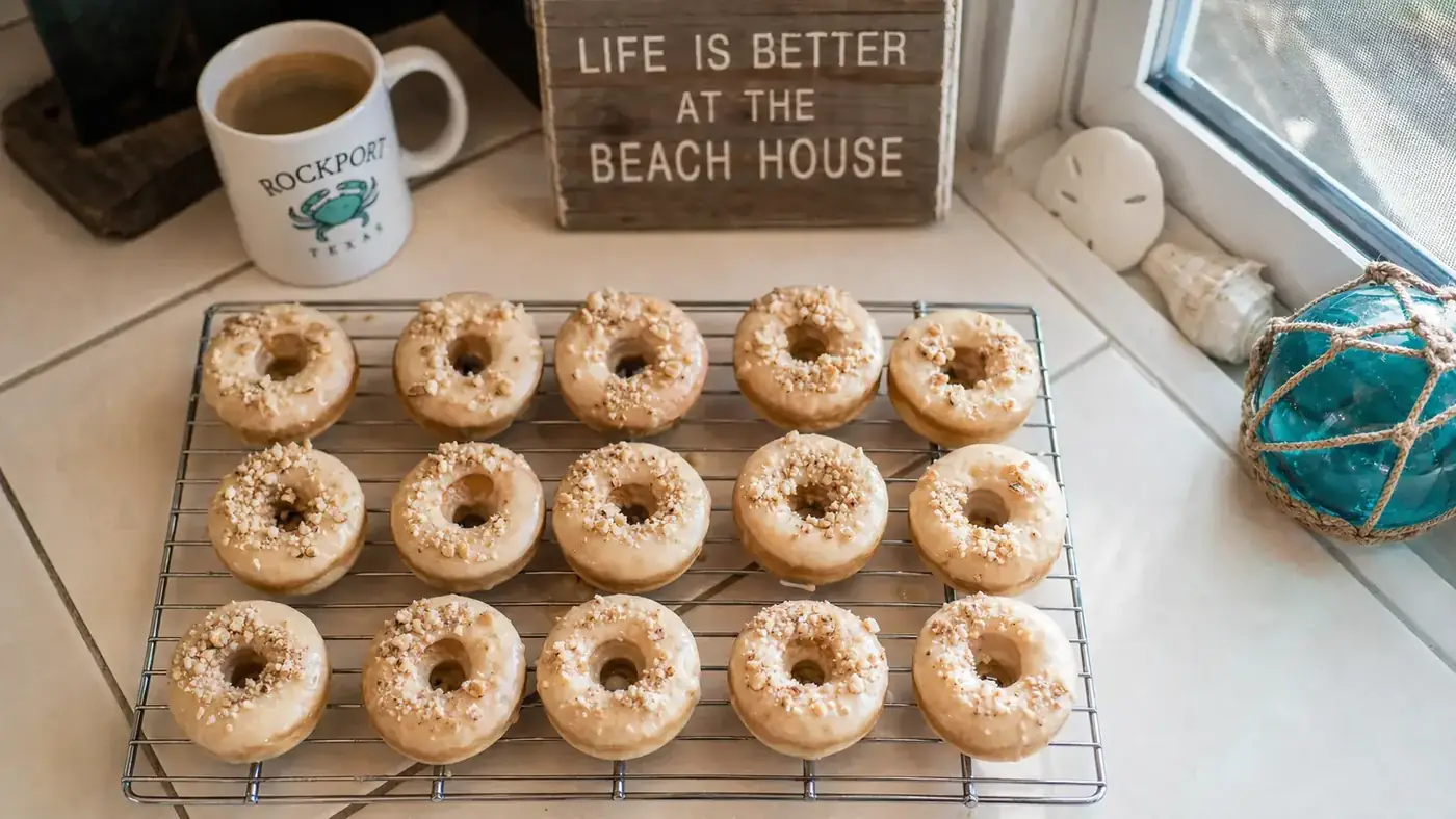 A tray of golden bakery-style mini donuts cooling on a wire rack in a warm kitchen
